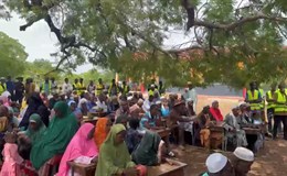 Viele Gäste sitzen auf den Schulbänken und verfolgen die Reden