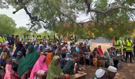 Viele Gäste sitzen auf den Schulbänken und verfolgen die Reden